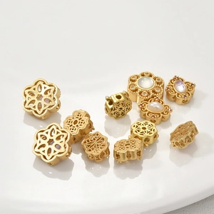 Matte gold snowflake and pearl spacer beads for DIY jewelry making on white background