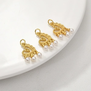 Close-up of golden hollow heart charms with small white pearls for DIY jewelry making