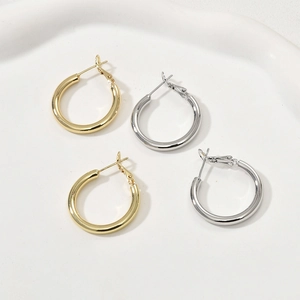 Vue macro de boucles d'oreilles créoles minimalistes plaquées or 14k et argent en plateau