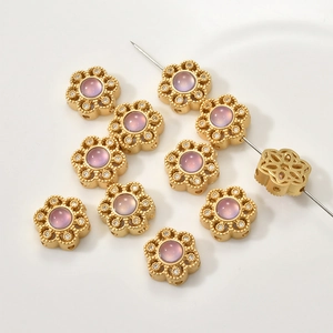 Macro detail of gold flower charm with purple stone and pave cubic zirconia beads