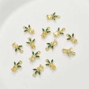 Macro detail of 14k gold-plated pineapple charms with yellow and green cubic zirconia
