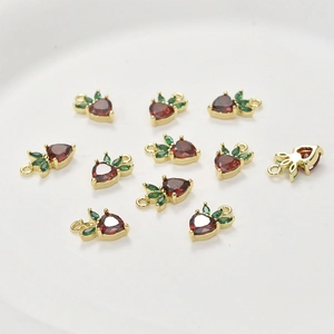 Detailed view of strawberry fruit charms with red heart crystals and gold setting for DIY jewelry