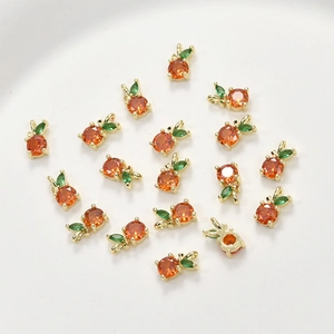 Macro detail of 14k gold plated fruit pendants with orange and green zircon crystals