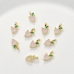 Detail of 14k gold plated peach pendants with pink heart stones and green leaves