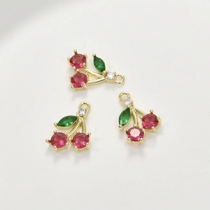 Macro shot of three cherry pendants with red and green cubic zirconia in 14k gold plating