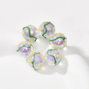 Nahaufnahme bunter Acrylperlen mit lila Kernen und grünen Wellenmustern für DIY-Schmuck