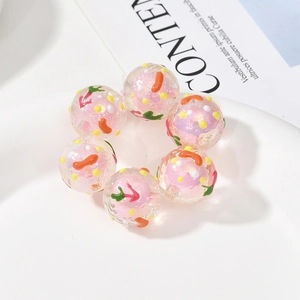 Nahaufnahme von rosa Acrylperlen mit bunten Punkten und Karottenmotiven für DIY-Schmuck