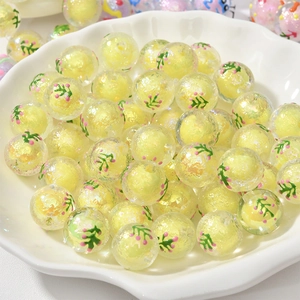 Nahaufnahme gelber Acrylperlen mit Blumenmuster in einer weißen Keramikschale