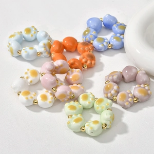 Colorful ceramic cat paw bead rings with golden spacers on a clean white background