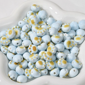 Detailed close-up of light blue ceramic cat paw beads for DIY jewelry making and crafts