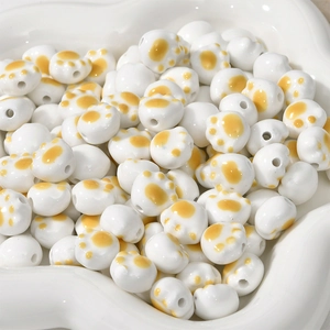 Macro detail of cat paw ceramic beads with yellow paw prints and center holes for DIY crafts