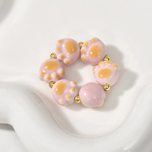 Detail of pink ceramic cat paw beads and gold spacers on a white display tray