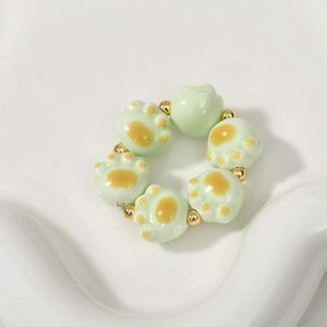 Macro shot of green ceramic cat paw beads with gold spacers for DIY jewelry making