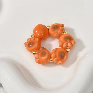 Macro detail of glossy ceramic cat paw beads with golden accents on a white wavy tray