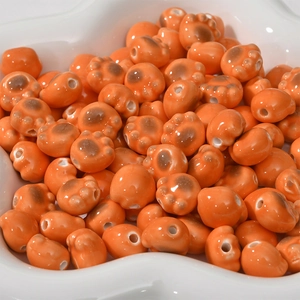 Macro shot of orange ceramic cat paw beads with glossy finish for DIY jewelry crafting