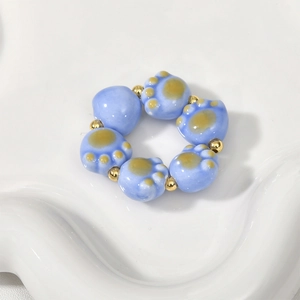 Macro shot of blue ceramic cat paw beads and gold metal beads for jewelry making