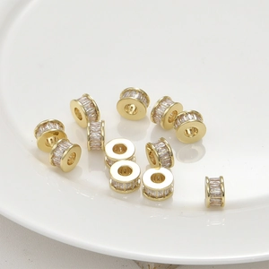 Macro detail of 14k gold plated spacer beads with baguette zircon on white plate
