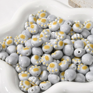 Macro shot of gray ceramic cat paw beads with yellow accents in a white flower dish