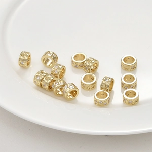 Macro detail of 14k gold plated cylinder spacer beads with star moon patterns and zircons