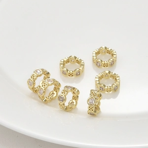 Close-up of 6 gold-plated barrel beads with hollow coin patterns and square zircons