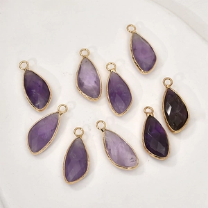 Macro detail of faceted teardrop purple crystal charms with gold metal edges