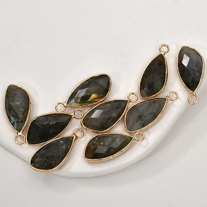 Detailed view of teardrop faceted labradorite pendants with gold plated metal edges