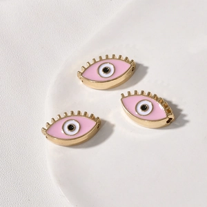 Detailaufnahme rosa Evil-Eye-Perlen mit Goldrand auf weißem Keramikteller