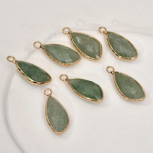 Macro detail of seven faceted green stone teardrop pendants with gold textured borders