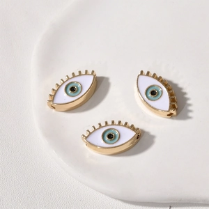 Detailansicht von drei blauen Evil Eye Anhängern mit goldenen Metallwimpern für DIY-Schmuck