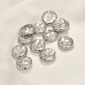 Dettaglio macro di perle piatte argento martellate per la creazione di gioielli fai da te