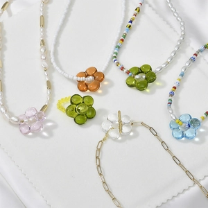 Macro detail of colorful translucent resin flower charms on assorted pearl bead chains