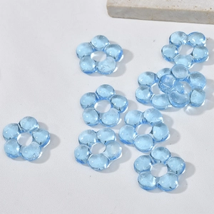 Macro detail of eight light blue transparent glass flower beads for DIY jewelry making