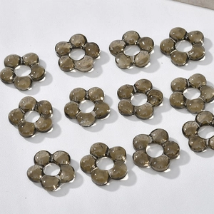 Macro detail of twelve smoky grey hollow flower beads for DIY jewelry making accessories