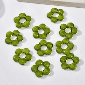 Close-up of ten green translucent flower glass beads for DIY jewelry making