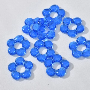 Close-up of blue translucent glass flower charms with hollow five-petal design for DIY jewelry