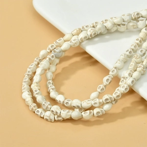 Gros plan de perles crânes en pierre synthétique crème avec textures marbrées grises