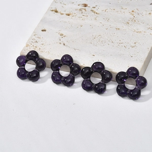 Detail of four purple translucent glass flower beads for DIY jewelry making and crafts