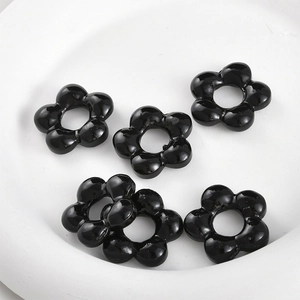 Detail of five black resin flower beads with central holes for DIY jewelry making