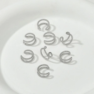 Minimalist silver C-shaped ear cuffs with beaded texture displayed on a white plate