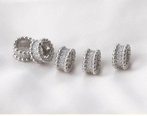 Macro view of five silver barrel beads with pavé cubic zirconia and milgrain edges