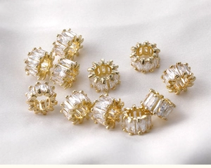 Detailed view of 14k gold-filled barrel beads with baguette-cut zircon on white silk