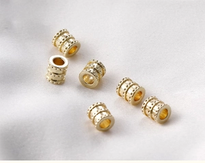 Macro detail of six 14k gold plated barrel beads with textured dot pattern for DIY jewelry