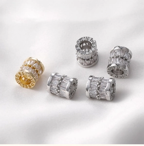 Macro detail of gold and silver cylinder beads with cubic zirconia and BELOVED engraving