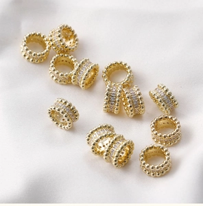 Macro view of 14k gold-plated barrel beads with sparkling white zircons for jewelry DIY