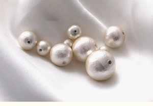 Macro shot of white cotton pearl beads with pre-drilled holes for DIY jewelry making