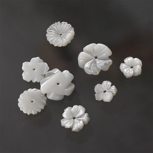 Detailed view of hand-carved white mother of pearl flower beads for jewelry making