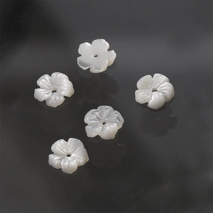 Detailed view of five white carved mother-of-pearl flower charms for DIY jewelry making