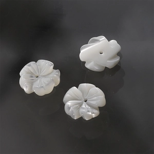 Detailed view of carved white shell flower beads for DIY jewelry with center drill holes