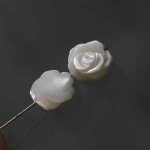 Macro view of hand-carved white mother of pearl rose flower on a delicate gold metal pin