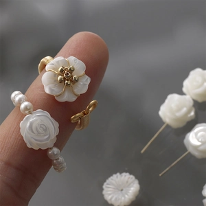 Macro shot of hand-wrapped wire rings with white carved shells and faux pearls